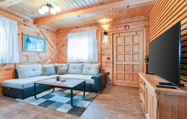 A cozy cabin interior with a sofa, coffee table, and a television. - Gorgeous home in Lovrecan with sauna (Lovrecan)