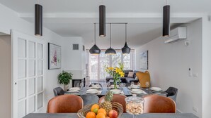 A dining area with a long table set for six, featuring a fruit bowl, a glass jar of cookies, and a pineapple centerpiece. - Beautiful home in Plano (Plano)