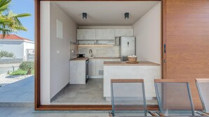 A compact kitchen with a built-in refrigerator, a sink, and a small dining area with metal chairs. - Beautiful home in Plano (Plano)