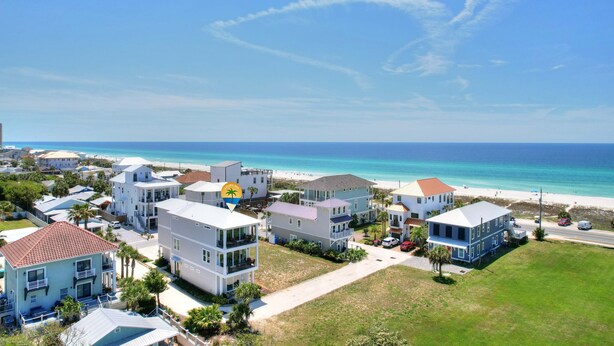 A coastal residential area with houses, a beach, and a clear sky.