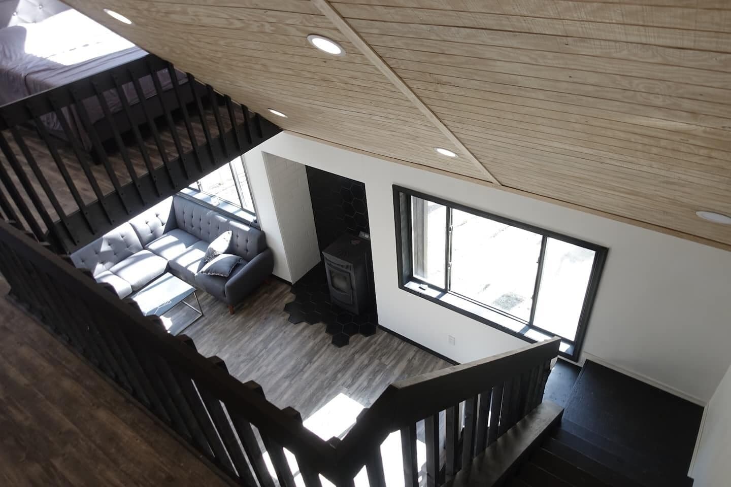 Un interior moderno con una escalera, un conjunto de sofás y una chimenea.