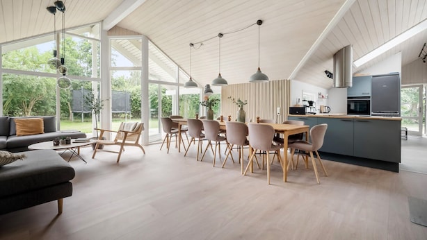 Ampla sala de estar com mesa e cadeiras de jantar, um sofá e área de cozinha com eletrodomésticos modernos.