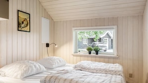 Quarto com cama, janela com vista para uma casa e um carro, luminária na parede e um quadro emoldurado.