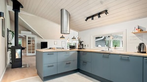 Uma cozinha moderna com ilha central, eletrodomésticos embutidos e uma janela grande que traz luz natural.