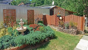 Un giardino con una fontana, diverse piante e un recinto in legno.