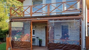 Una struttura in legno a due piani con un balcone, una porta in vetro e un interno con pareti in mattoni.