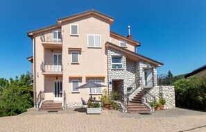 Ein mehrstöckiges Gebäude mit einer Stein-Fassade, einem Balkon und einer Treppe, die zum Eingang führt.