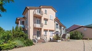 A multi-story residential building with balconies, a paved driveway, and surrounding greenery. - Cozy apartment in Jadranovo with house sea view (Jadranovo)