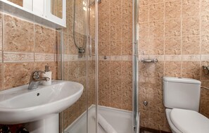 Ein Badezimmer mit einer begehbaren Duschkabine, einem weißen Waschbecken und einer Toilette.