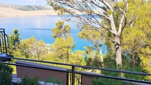 A balcony with a view of a lake and surrounding trees. - Cozy apartment in Jadranovo with house sea view (Jadranovo)