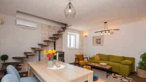 Ein modernes Wohnzimmer mit einem Holzesstisch, einem grünen Sofa und einer Treppe mit Holzstufen.