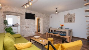 Ein Wohnzimmer mit einem grünen Sofa, einem gelben Sessel und einem Holzespeisetisch mit blauen Kissen.