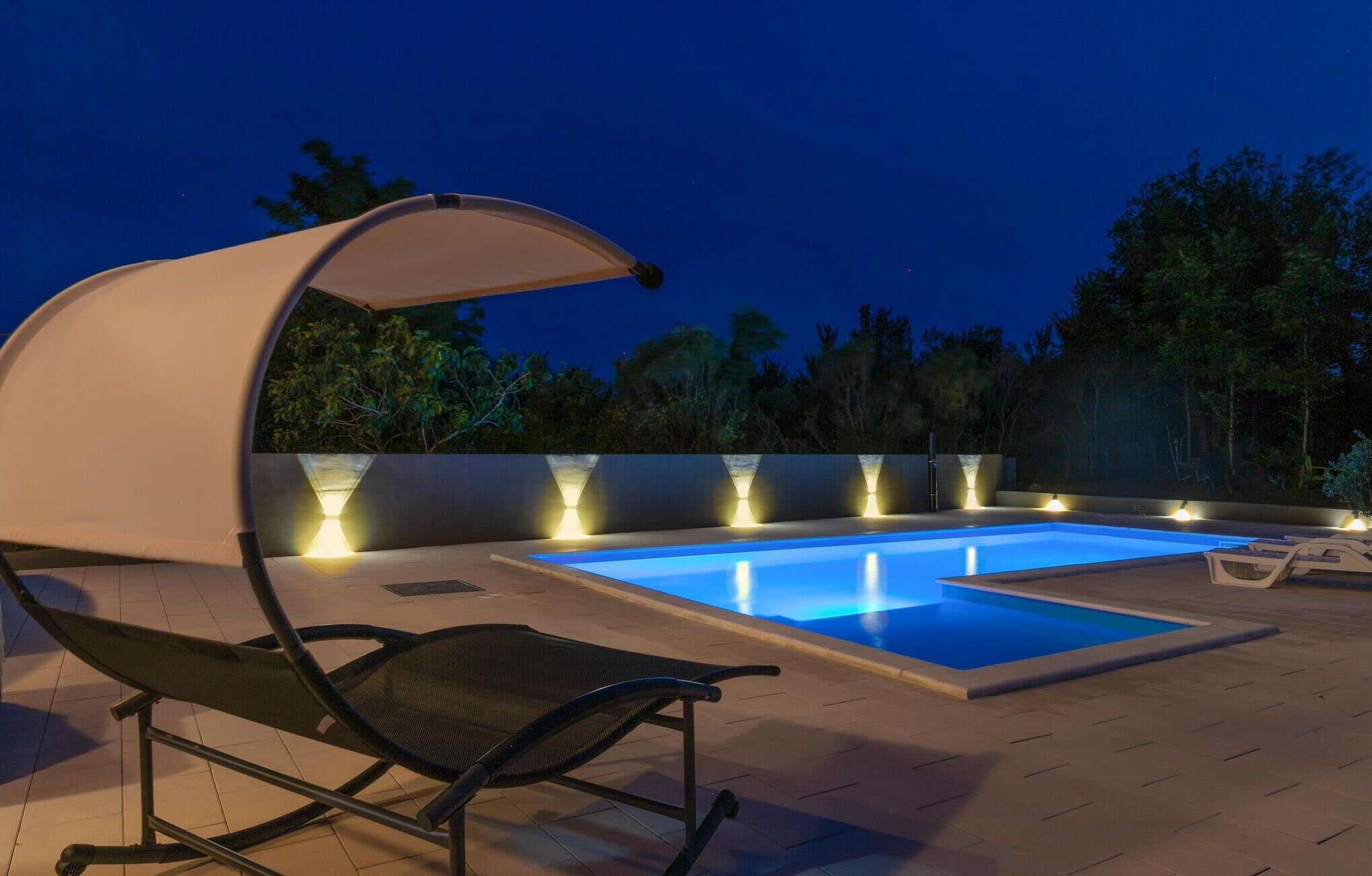 A swimming pool with a covered seating area and a chair.