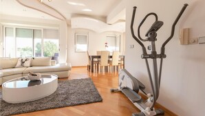 Een moderne woonkamer met een bank, salontafel en sportapparatuur.
