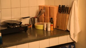 Una cocina con estufa, ollas, tabla de cortar y bloque de cuchillos.