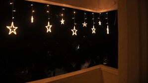 Habitación con vista nocturna, luces colgantes en forma de estrella y ventana que da a un exterior oscuro.