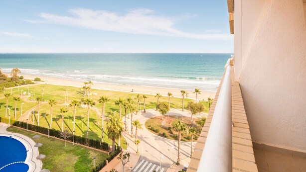 Un balcón con vista a la playa y una piscina.