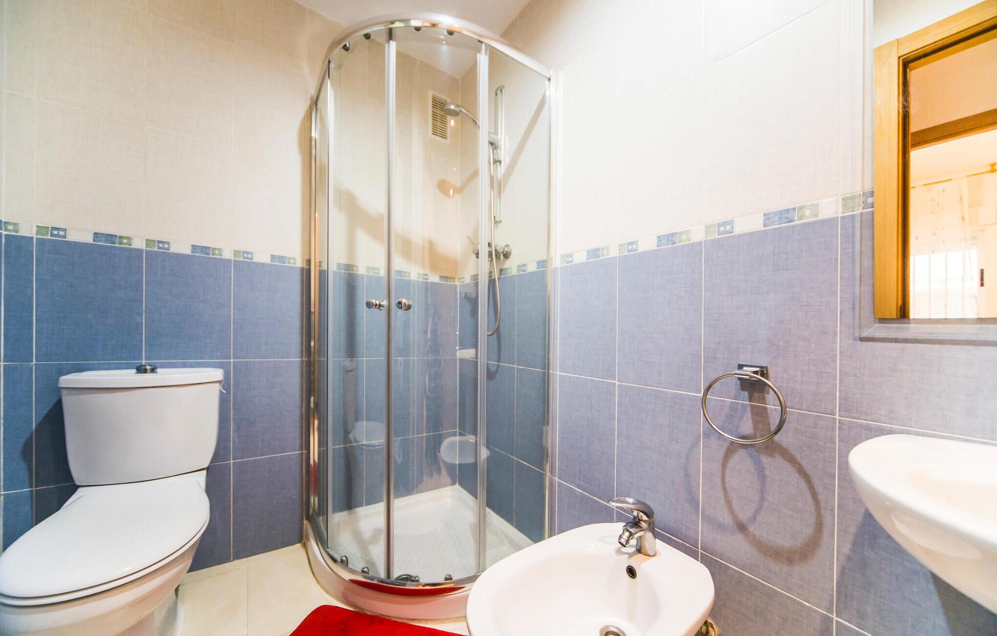 Une salle de bain avec une douche à parois de verre, des toilettes et un lavabo.
