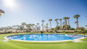 Una piscina con una zona verde circundante y palmeras.