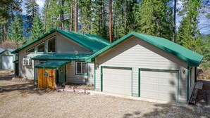 Een chalet met twee verdiepingen, een groen dak en een garage.