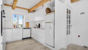 Eine moderne Küche mit weißen Schränken, einem eingebauten Geschirrspüler und einer Holzbalkendecke.