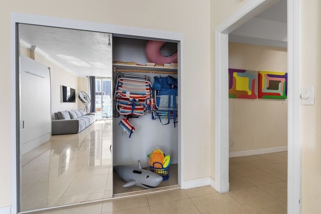 Una habitación con una puerta corredera que da a un armario con varios objetos, como bolsos y un juguete.