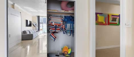 Una habitación con una puerta corredera que da a un armario con varios objetos, como bolsos y un juguete.