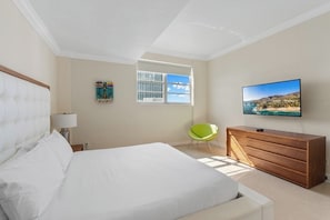 Une chambre d’hôtel avec un lit, une télévision, une commode, une chaise et une fenêtre donnant sur un beau paysage.