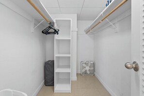 A narrow hallway with a white shelving unit, a fan, and a door with a round handle.