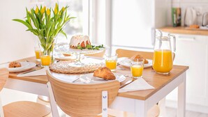 Ein Frühstückstisch mit Holzoberfläche, Tellern mit Speisen, Gläsern Orangensaft und einer Saftkanne.