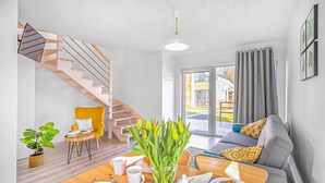Ein modernes Wohnzimmer mit einer Holztreppe, einem Essbereich mit Frühstücksangeboten und Blick nach draußen.