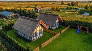 Une propriété rurale comprenant deux charmantes chaumières, une cour clôturée et un ensemble de jeux avec une balançoire.