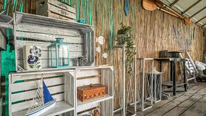 Un intérieur rustique avec des étagères en bois où sont exposés divers objets, comme une maquette de voilier bleu, un pot en céramique et un coffre en bois.