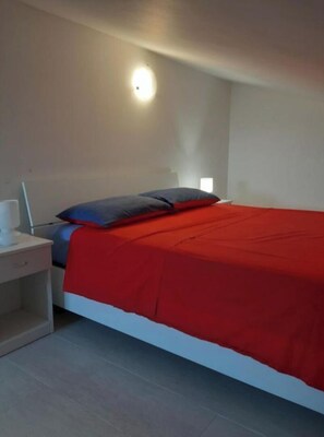 Une chambre à coucher avec un lit, une table de chevet et une lampe fixée au mur.