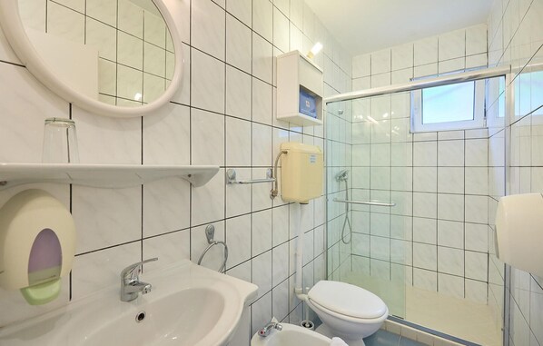 A modern bathroom with a sink, mirror, toilet, and glass shower enclosure.