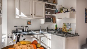 A kitchen with white cabinets, a microwave, a stove, and a bowl of fruit. - GOLD APARTMENT AREZZO CENTER (Arezzo)