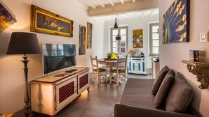 A living room with a TV, sofa, and dining area with chairs and a table. - GOLD APARTMENT AREZZO CENTER (Arezzo)