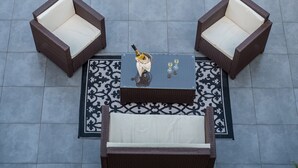 A patio area with two wicker chairs and a table, a bottle of champagne, and a decorative rug. - GOLD APARTMENT AREZZO CENTER (Arezzo)