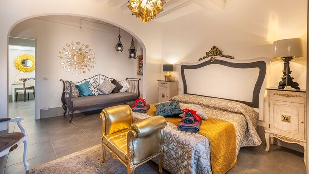 A bedroom with a bed, a sofa, a chair, a nightstand, and a lamp. - GOLD APARTMENT AREZZO CENTER (Arezzo)