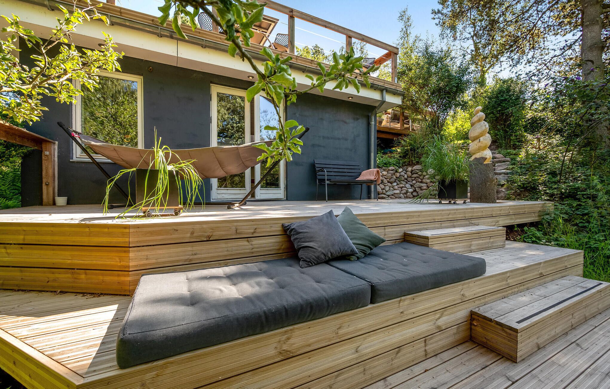 A modern outdoor deck with a built-in sofa and a hammock.