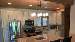 A modern kitchen with white cabinets, stainless steel appliances, and a central island with chairs.