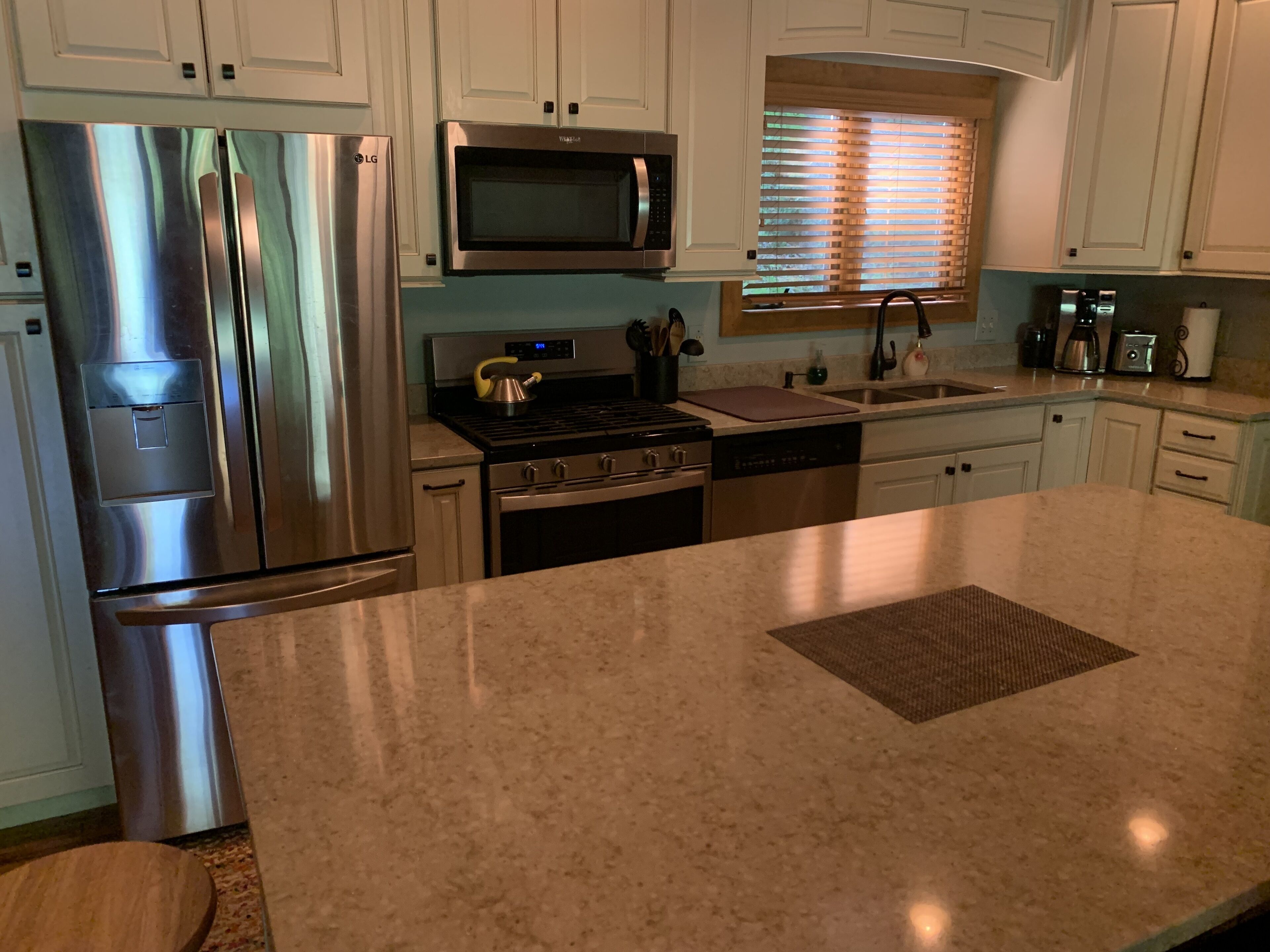 A modern kitchen with stainless steel appliances, a microwave, and a large island.