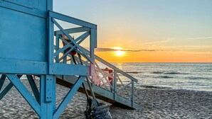 Una torre de socorristas en una playa, con un atardecer de fondo.