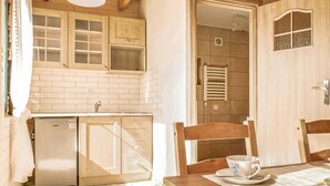 Cocina compacta con refrigerador integrado, pileta y alacenas de madera.