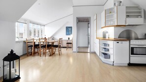 Eine moderne Küche mit Essbereich, ausgestattet mit einem Holztisch und -stühlen, weißen Schränken und einem eingebauten Backofen.