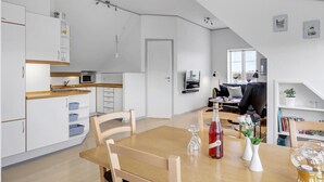 Eine moderne Küche mit weißen Schränken, einer Holzarbeitsplatte und einem Essbereich mit Tisch und Stühlen.