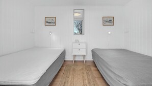Ein Zimmer mit zwei Einzelbetten, einem kleinen weißen Schminktisch und zwei Wandleuchten.
