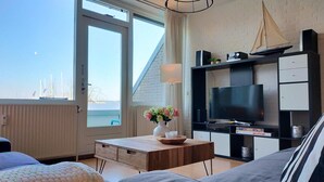 Ein modernes Hotelzimmer mit großem Fenster, Flachbildfernseher, Holztisch und einem Modell eines Segelbootes an der Wand.
