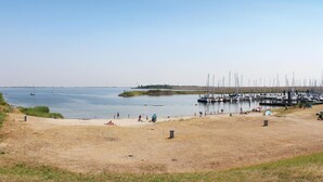 Ein Strand mit einer Marina, sandigem Ufer und Booten.