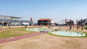 Ein öffentlicher Platz mit einem Pool, Bänken und einem SUP Store.